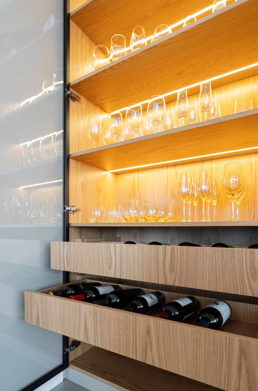 Lit glass shelves for glassware above wood wine drawers