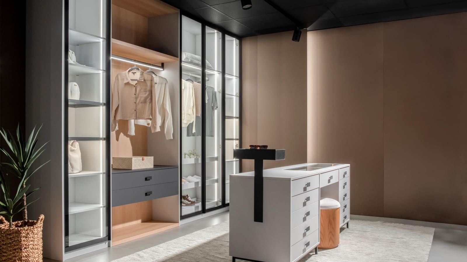 Dressing room with lit glass-front wardrobes and a central chest of drawers