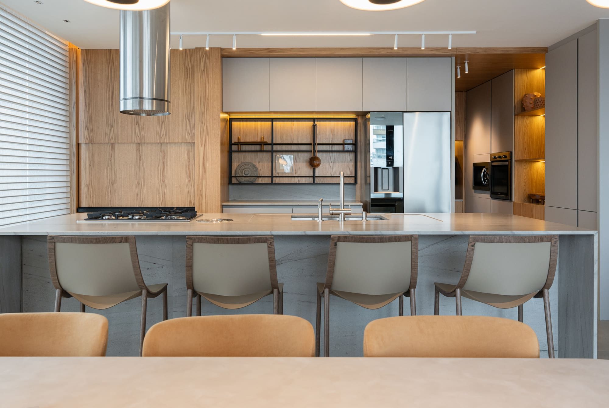 Wood and grey kitchen with a long island, a stainless hood and lit open shelving