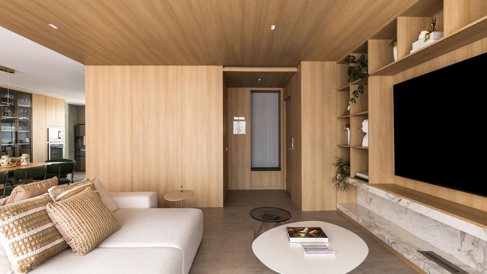 Living room wrapped in light wood with built-in shelving around the TV and a stone ledge